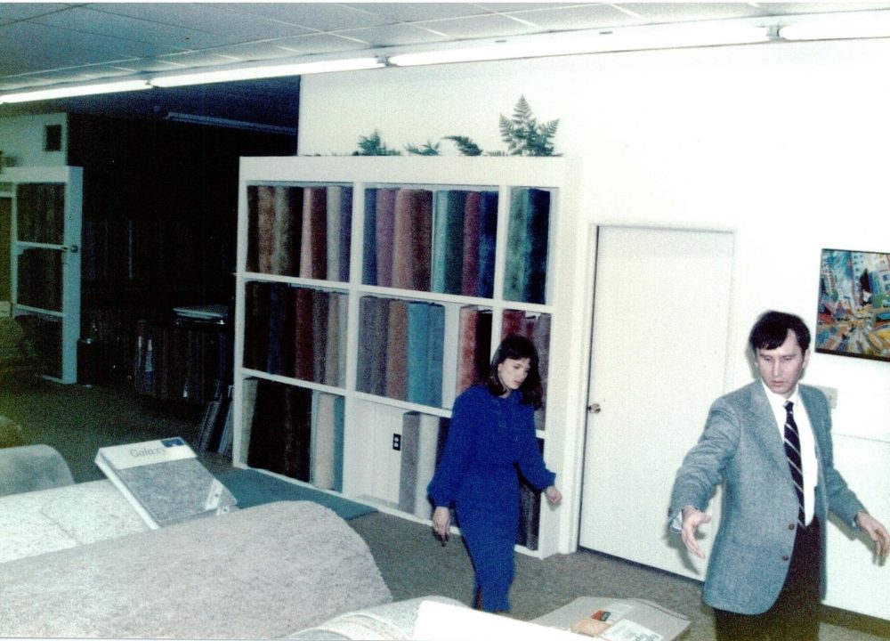 The Carpet Shoppe's employee, Dennis, shows a customer around the showroom in the 1980s.